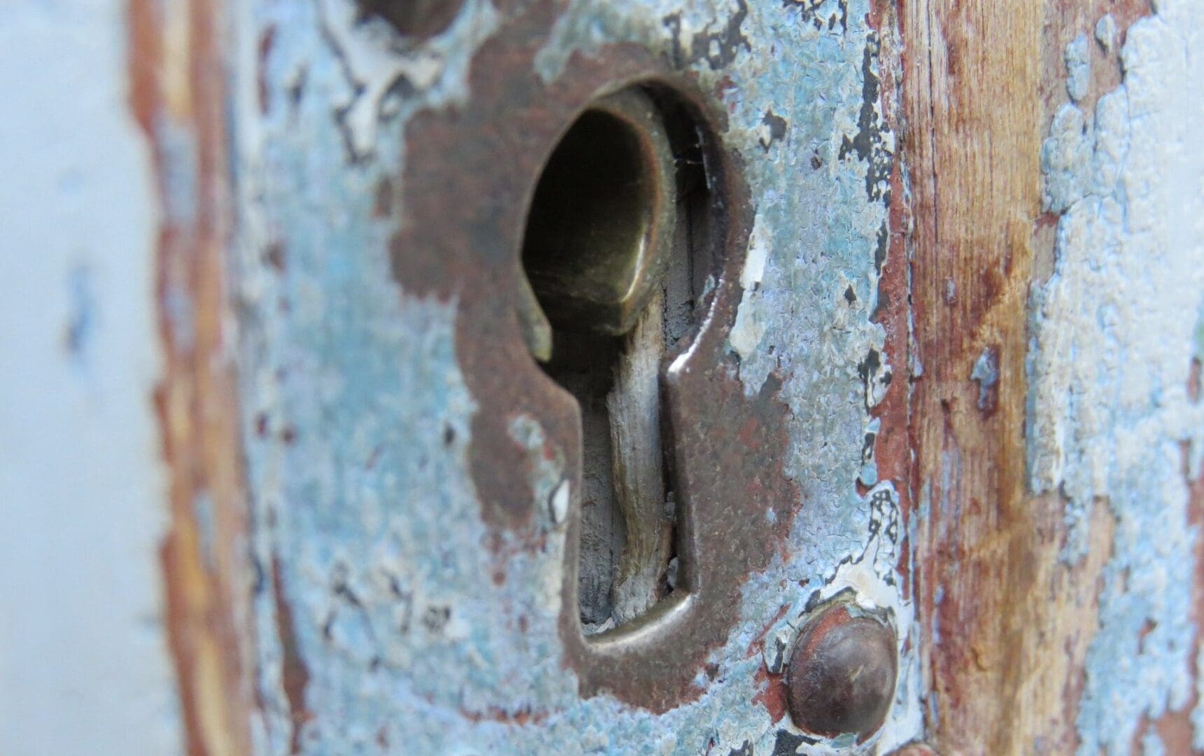 Rusty keyhole in weathered wooden door.