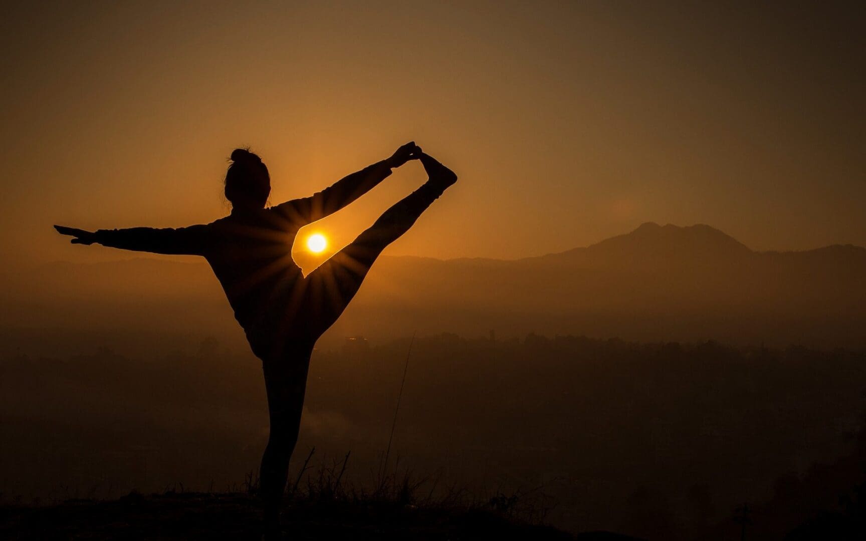 Silhouette of person doing yoga at sunset.