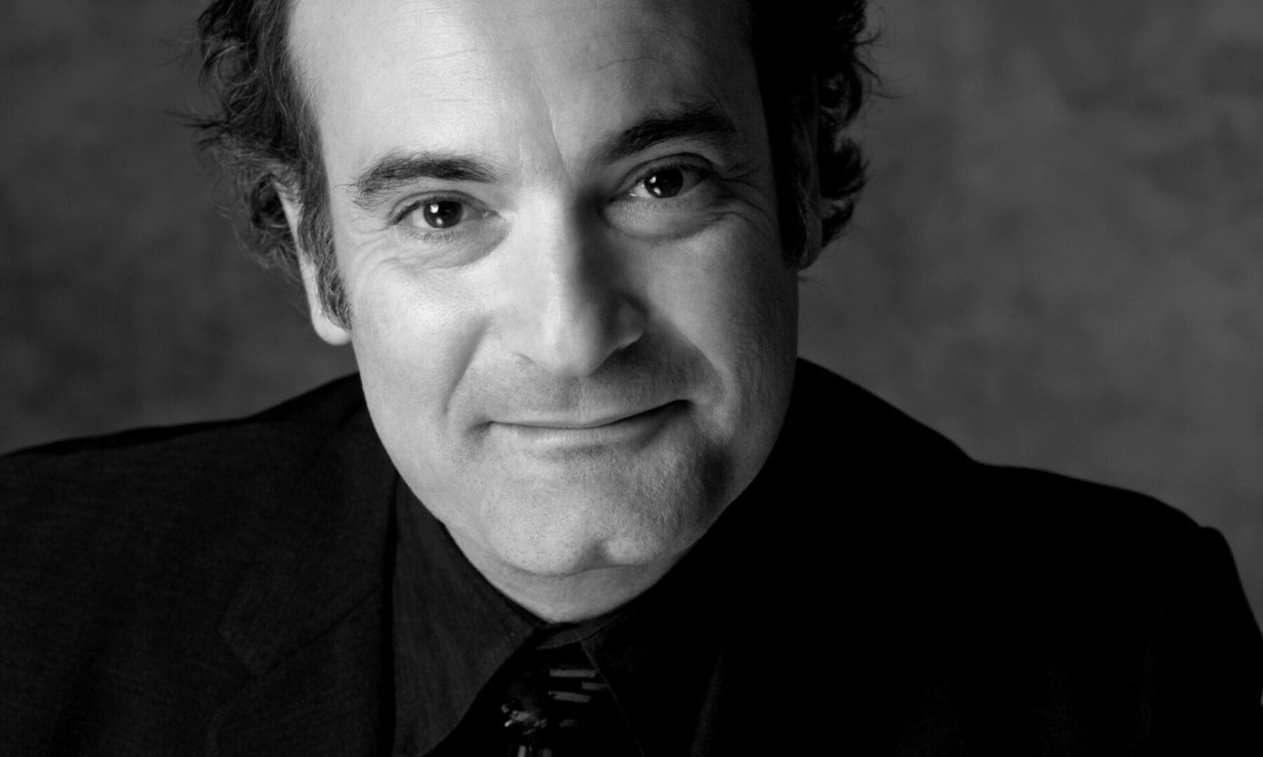 Smiling man in black and white portrait.