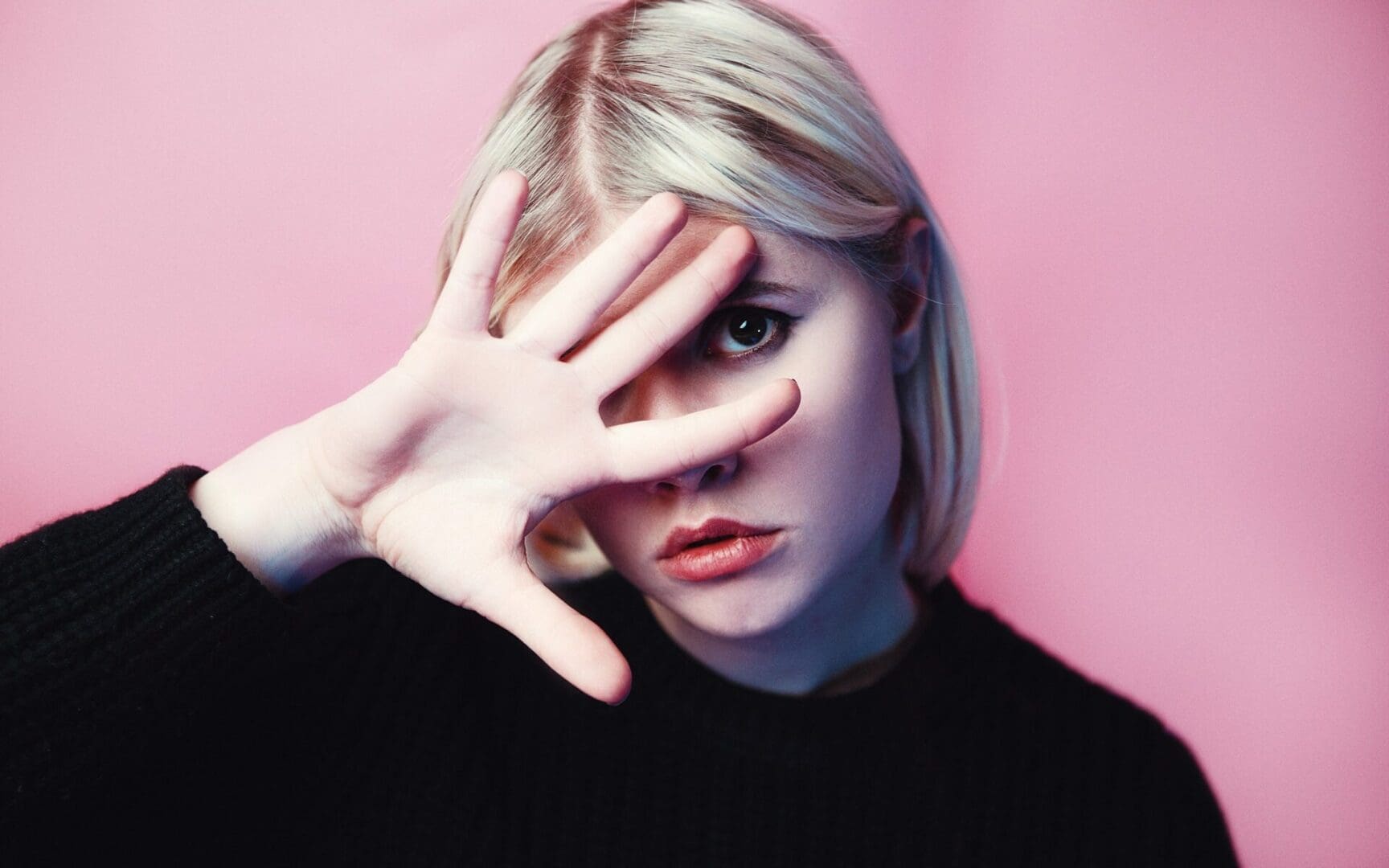Person posing with hand covering one eye.