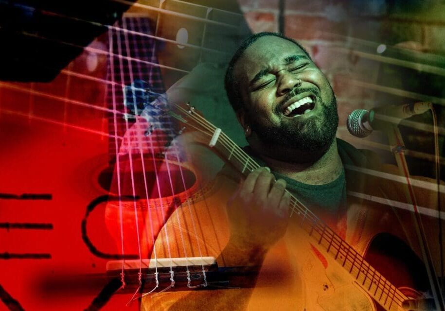 Singer passionately performing with guitar on stage.